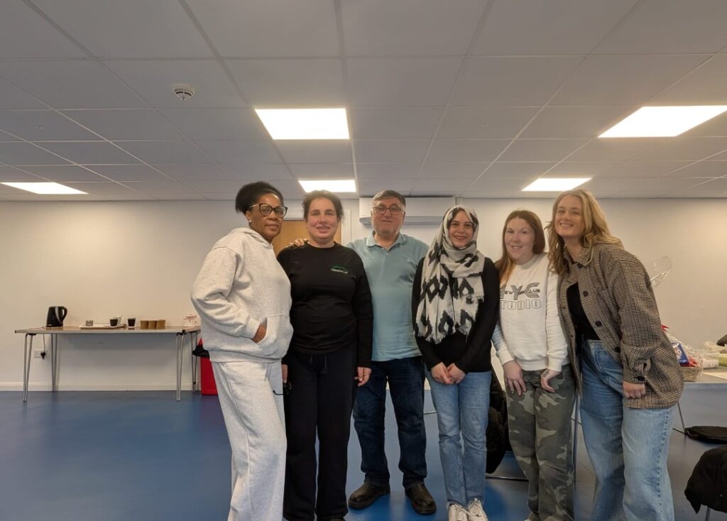 Six people standing in a room, smiling at the camera